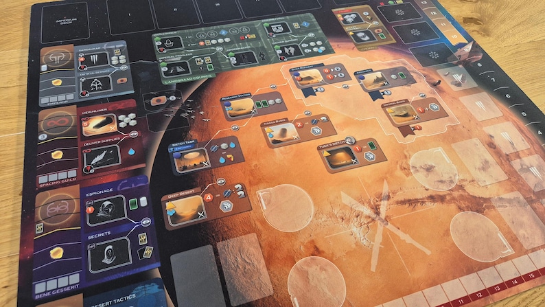 May include: A board game with a Martian theme. The game board is predominantly orange and brown, depicting a map of Mars. Various game pieces, cards, and player boards are arranged on the board. The game components feature detailed illustrations and text, enhancing the strategic gameplay.