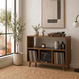 Può includere: Mobile consolle per giradischi in stile moderno della metà del secolo, in legno marrone caldo. La consolle presenta vani aperti per dischi in vinile, un giradischi e oggetti decorativi. È visibile un album di Miles Davis.
