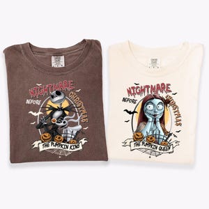 May include: A brown t-shirt and a cream t-shirt featuring graphic prints from The Nightmare Before Christmas. The brown shirt displays Jack Skellington and Zero with the text The Pumpkin King. The cream shirt shows Sally with the text The Pumpkin Queen.