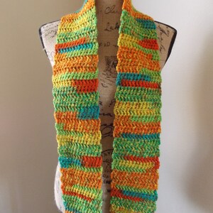 May include: A colorful, handmade crochet scarf. The scarf features horizontal stripes of orange, yellow, green, and teal. The scarf is displayed on a mannequin. This accessory is perfect for adding a pop of color to any outfit.