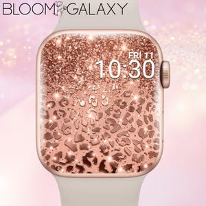 Könnte beinhalten: Eine Smartwatch mit einem hellen Armband und einem roségoldenen Metallrahmen. Das digitale Display zeigt ein roségoldenes Glitzer-Leopardenmuster mit dem Text "BLOOM GALAXY" oben sowie dem Datum "FRI 11" und der Uhrzeit "10:30" in Weiß.