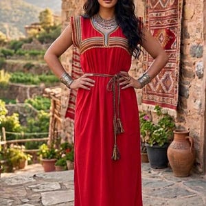 K&ouml;nnte beinhalten: Ein leuchtend rotes, &auml;rmelloses, bodenlanges Kleid mit V-Ausschnitt und aufwendiger, mehrfarbiger Webkante an Schultern, Ausschnitt und Saum. Das Kleid verf&uuml;gt &uuml;ber ein d&uuml;nnes, geflochtenes Taillenband mit Quasten an den Enden.