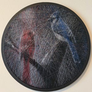 Pode incluir: Peça de arte em fio redonda com dois pássaros. Um pássaro é renderizado em fio azul e branco, o outro em vermelho e branco. Os pássaros estão em um fundo preto, emoldurados por uma borda circular preta.
