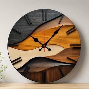Op de afbeelding: Een ronde wandklok met een gelaagd, golvend ontwerp van hout in verschillende tinten zwart, donkerbruin, lichtbruin en crème. De wijzerplaat heeft zwarte uurmarkeringen en zwarte wijzers, met een dunne rode secondewijzer in het midden.