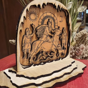 May include: A wooden laser-cut decorative piece depicting a mythological scene. The artwork features figures, a bull, and celestial elements like the sun and moon. The piece is mounted on a layered base, showcasing intricate details and a natural wood finish.