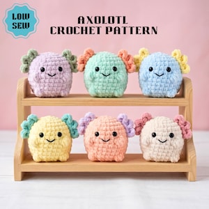 Puede incluir: Seis ajolotes de ganchillo de colores pastel en tonos morado, verde, azul, amarillo, melocotón y crema, cada uno con una cara sonriente y branquias rizadas. Los ajolotes se exhiben en una pequeña estantería de madera. El texto de la imagen dice "AXOLOTL CROCHET PATTERN" y "LOW SEW".