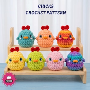 May include: Seven round, plush crochet chicks in various colors including teal, orange, yellow, green, pink, and purple, each with a red crest, orange beak, and large eyes. The text CHICKS CROCHET PATTERN and NO SEW is visible.