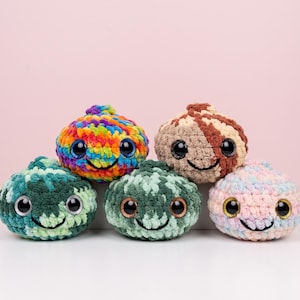 May include: Five round, plush, crocheted toys with large, glossy black eyes and stitched smiles. The toys feature varied color patterns including a rainbow variegated yarn, a brown and cream swirl, two shades of green, and a soft pink and blue mix.