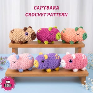 May include: Six plush capybara toys made of chunky yarn in various colors including brown, magenta, peach, pink, purple, and light pink. The text CAPYBARA CROCHET PATTERN and NO SEW is visible. Each toy features small ears and embroidered details.