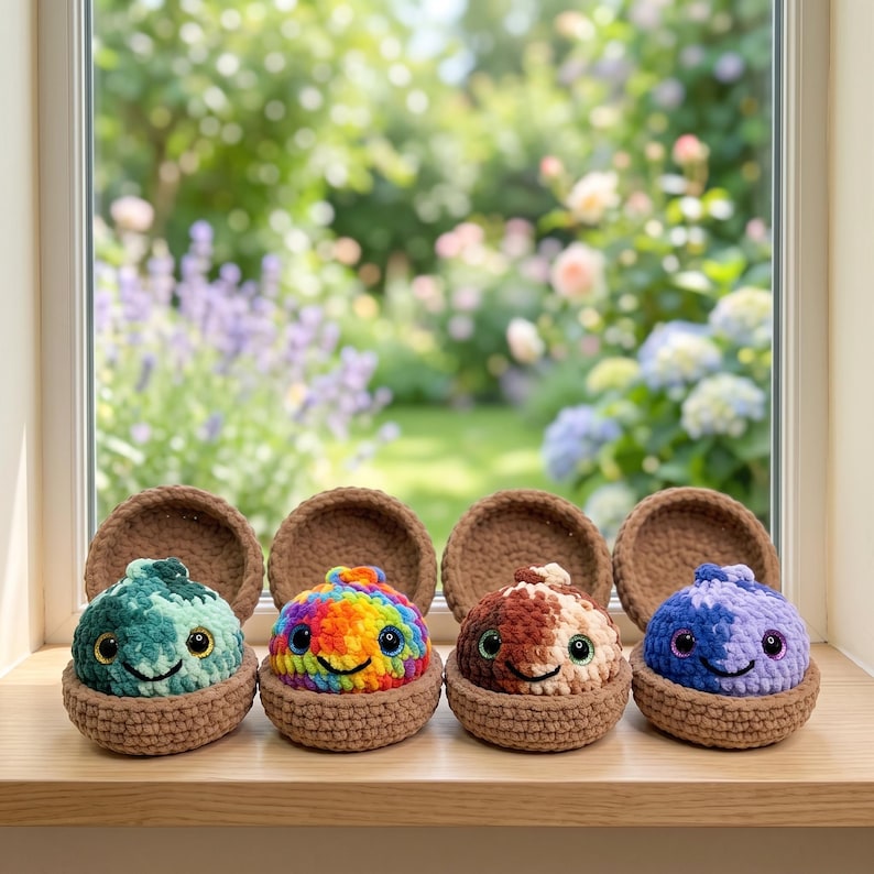 May include: Four small, round, crocheted plush creatures with large black eyes and stitched smiles, each nestled inside a brown crocheted shell. The creatures feature variegated yarn patterns in shades of green, rainbow, brown, and purple.