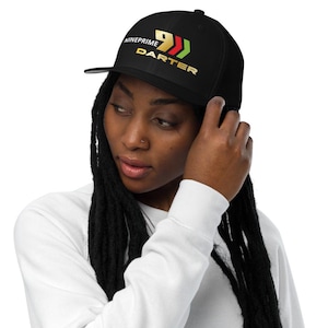 Può includere: Un cappellino da baseball nero con la scritta NINEPRIME DARTER in lettere dorate, accompagnata da un numero nove dorato stilizzato e due frecce a chevron rosse e verdi, posizionati sul pannello frontale della corona strutturata.