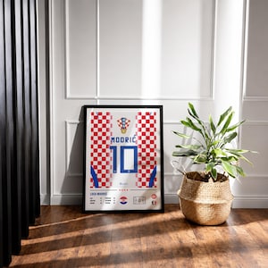 May include: A framed rectangular poster featuring a red and white checkered pattern inspired by the Croatian national soccer jersey. The design displays the name MODRIĆ, the number 10, the HNS crest, and player statistics in blue and black text.