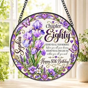 Könnte beinhalten: Ein rundes Hängeschild mit einem Rand im Buntglas-Stil, verziert mit violetten Schwertlilien, Lavendel und Schmetterlingen. Der Text lautet: Sophia, Chapter Eighty, BEHIND YOU ALL YOUR MEMORIES before you all your dreams AROUND YOU ALL WHO LOVE YOU within you all you need Happy 80th Birthday!