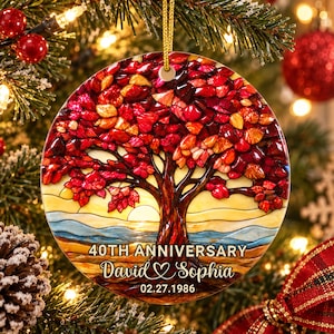 Op de afbeelding: Een rond keramisch ornament met een boom in glas-in-loodstijl met rode en oranje bladeren. De tekst luidt 40TH ANNIVERSARY, David & Sophia en 02.27.1986. Het ontwerp bevat een gouden zon, een blauwe horizon en een gouden ophangkoord.