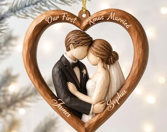 May include: A heart-shaped wooden ornament featuring a carved couple in wedding attire. The text "Our First Xmas Married" is engraved at the top, with the names "James" and "Sophia" engraved on the lower left and right sides of the frame.