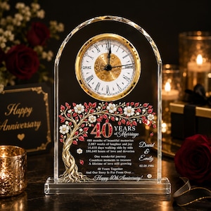 May include: An arched clear crystal clock featuring a gold-rimmed face with Roman numerals. The surface displays a golden tree with red and white floral accents, the text 40 Years of Marriage, David & Emily, 02.05.1986, and anniversary sentiments.