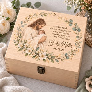 Peut inclure: Une boîte à souvenirs rectangulaire en bois clair avec une illustration imprimée de Jésus tenant un bébé dans une couronne florale. Le texte indique : ...and to think the first thing you saw when you opened your tiny little eyes was the face of Jesus. Baby Miller 06/12/26.