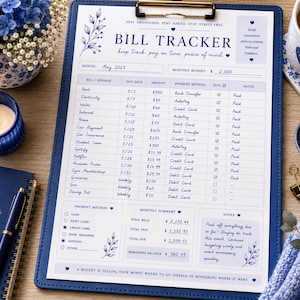 Puede incluir: Un rastreador de facturas azul sobre un portapapeles con un diseño floral. El rastreador incluye secciones para gastos, fechas de vencimiento, métodos de pago y notas. Un cuaderno azul, un bolígrafo y una vela están al lado del rastreador.