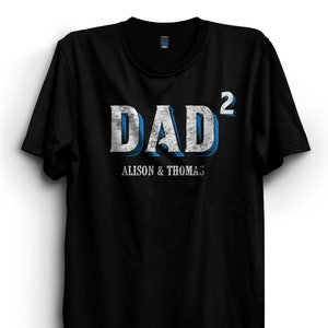 May include: Black t-shirt with a white and blue graphic that says "DAD²" with the text "ALISON & THOMAS" underneath.