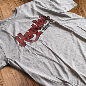 May include: A gray t-shirt with a red and black graphic that says "Hoosier Daddy?"