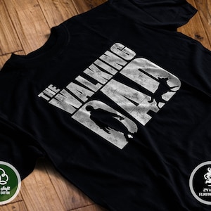 Puede incluir: Camiseta negra con un gr&aacute;fico blanco que dice "The Walking Dad" con una silueta de una persona y un perro.
