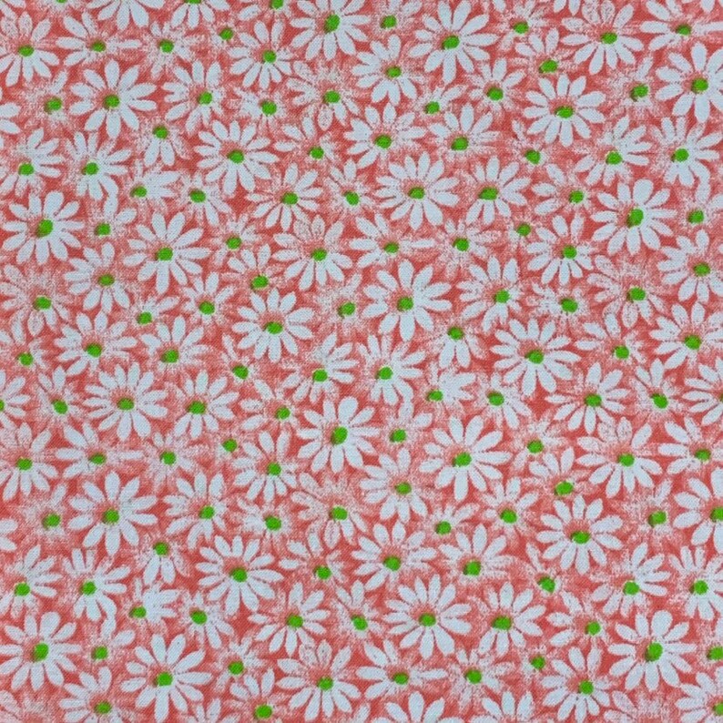 May include: A red fabric with a white daisy pattern. The daisies have green centers.