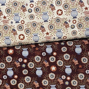 May include: Two fabric swatches with a repeating pattern of blue and white flower bouquets in vases with the text "1776" and "Bright Stars" on a beige and burgundy background.
