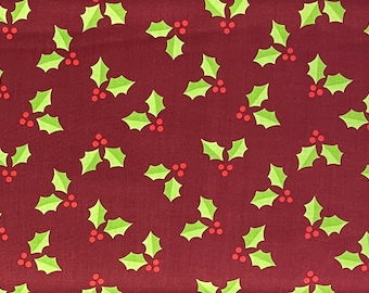 May include: A fabric with a repeating pattern of green holly leaves and red berries on a dark red background. The design is evenly spaced across the fabric, creating a festive holiday theme.