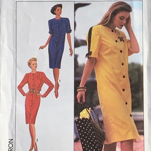 May include: A vintage sewing pattern featuring three different dress designs. The first dress is blue with a button-up front and short sleeves. The second dress is red with a button-up front and long sleeves. The third dress is yellow with a button-up front and short sleeves. The pattern includes instructions for making the dresses.