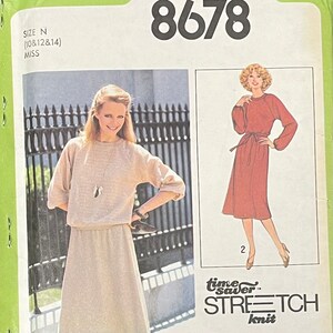 May include: A sewing pattern for a dress with a long skirt and a fitted bodice. The pattern is for sizes 10, 12, and 14. The pattern is called "Time Saver Stretch Knit" and has the number 8678 on it.
