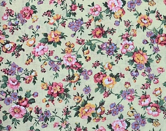May include: A floral fabric featuring a repeating pattern of pink, yellow, and purple flowers with green leaves on a pale yellow background. The design is dense and detailed, creating a vintage aesthetic.