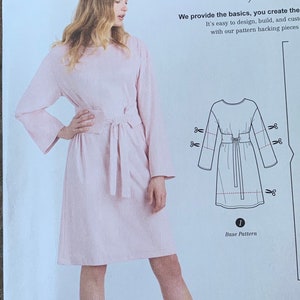 May include: A pink dress with long sleeves and a tie belt. The dress is shown on a model and a line drawing of the dress is shown next to the model. The text "We provide the basics, you create the... It's easy to design, build, and customize with our pattern hacking pieces" is shown above the image. The text "1 Base Pattern" is shown below the image.