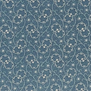 May include: A close-up of a blue fabric with a repeating white floral pattern. The design features stylized flowers and swirling vines, with small white dots filling the spaces between the larger elements. The fabric has a textured appearance.
