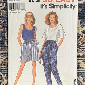 May include: A sewing pattern for women's pants and shorts. The pattern is for sizes 10-20 and is from Simplicity. The pattern shows two models wearing the pants and shorts. The pants are a floral print and the shorts are a striped print.