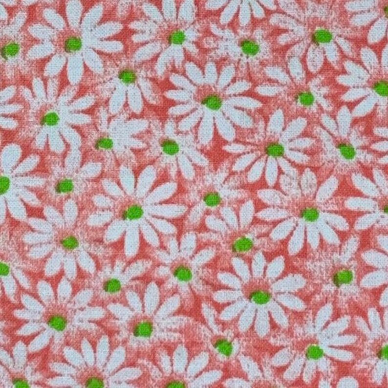 May include: A close-up of a fabric with a repeating pattern of white daisies on a coral background.