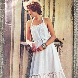 May include: A See & Sew by Butterick sewing pattern envelope, number 5797, size Medium 12-14. The front features a photograph of a white halter-neck dress with a lace-trimmed bodice, a tie waist, and a ruffled hemline, shown on a person.