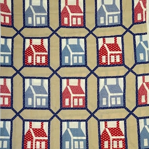 May include: A beige fabric with a repeating pattern of red and blue houses. The houses are outlined in navy blue and have white windows. The background is a light beige colour.