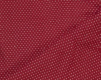 May include: Red fabric with a white polka dot pattern. The fabric has a subtle texture and a slightly wrinkled appearance.