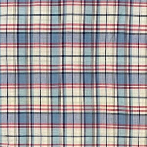 May include: A close-up of a fabric with a plaid pattern. The pattern features a grid of intersecting lines in shades of blue, red, and cream. The fabric appears to be cotton or a similar material, with a slightly textured surface.