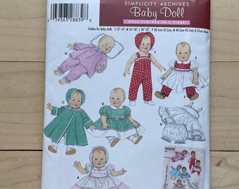 May include: A Simplicity pattern for making baby doll clothes. The pattern includes instructions for making a variety of outfits, including a green coat, a pink dress, a white dress, a red dress, and a white and pink dress. The pattern is designed by Teri.
