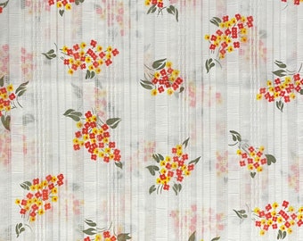 May include: White fabric with a repeating pattern of small red and yellow flowers. The fabric has a subtle striped texture.