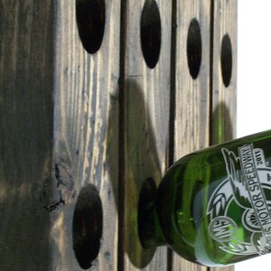 May include: A wooden wine rack with a green glass bottle of wine. The bottle has the text "Motor Speedway 2011" etched into it.