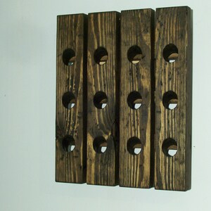 May include: A wooden wine rack with 12 bottle slots. The rack is made of dark brown wood with a rustic finish.
