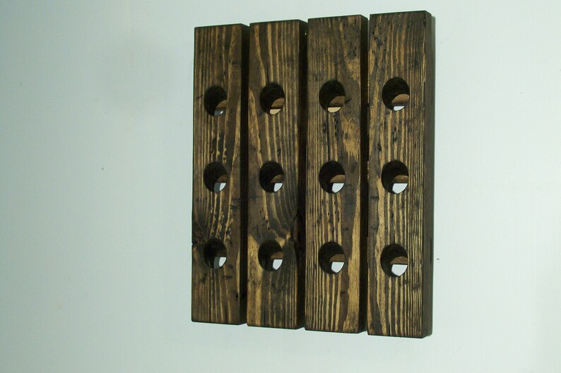 May include: A wooden wine rack with 12 bottle slots. The rack is made of dark brown wood with a rustic finish.