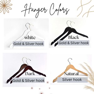 May include: A display of clothes hangers in white, black, dark wood, and natural wood finishes. The text reads Hanger Colors, white, Black, Dark, Natural, and Gold & Silver hook. Each hanger features a metal hook in either gold or silver.