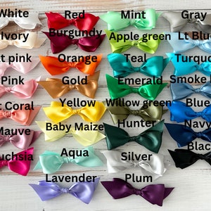 May include: A collection of satin bows in various colors, including white, red, pink, orange, yellow, green, blue, and black. Each bow is labeled with its corresponding color name, such as "White," "Red," and "Black."