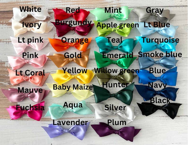 May include: A collection of satin bows in various colors, including white, red, pink, orange, yellow, green, blue, and black. Each bow is labeled with its corresponding color name, such as "White," "Red," and "Black."