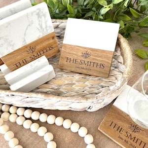May include: Set of four white marble coasters with a wood base. Each coaster features a small tree design and the text "THE SMITHS" with a date.