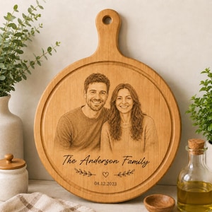 May include: A round wooden cutting board with a handle featuring a laser-engraved portrait of a couple. Below the portrait, the text reads The Anderson Family, followed by a small heart icon, leafy branches, and the date 04.12.2023.
