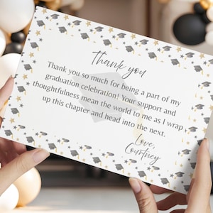 May include: A white rectangular graduation thank you card featuring a border of grey graduation caps and gold stars. The text reads: Thank you, Thank you so much for being a part of my graduation celebration! Your support and thoughtfulness mean the world to me as I wrap up this chapter and head into the next. Love, Courtney.